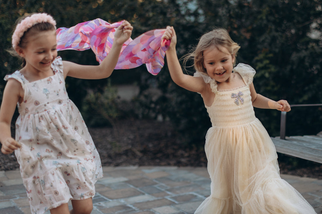 two young girls playing outdoors wearing light summer dresses