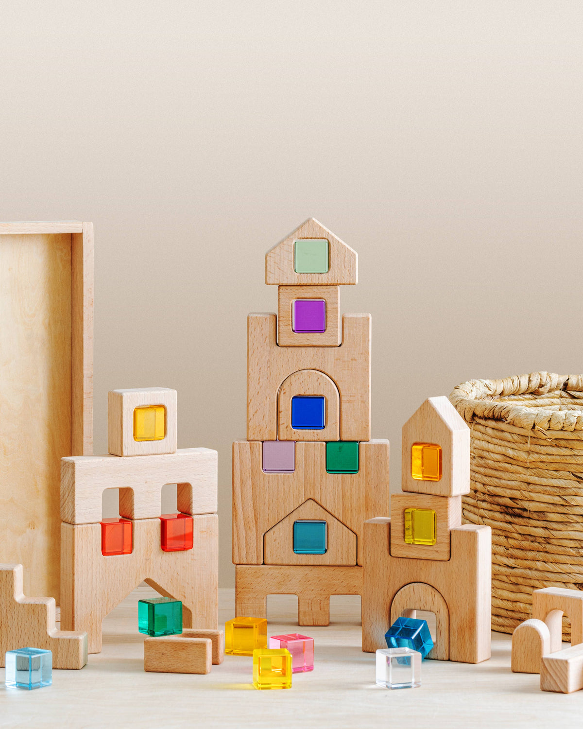 “Wooden blocks for toddlers stacked into a colorful open-ended building set with natural wood and translucent pieces.”
