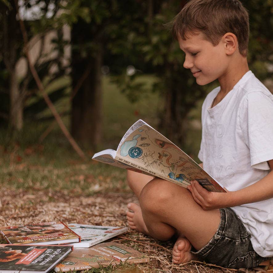 Child reading a book outdoors with nature in the background