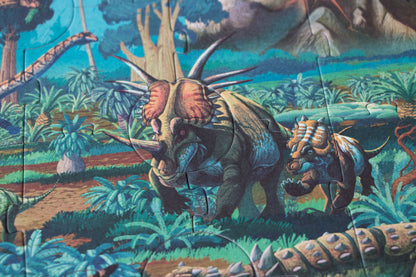 Dinosaur-themed fabric with a triceratops and other prehistoric creatures in a jungle setting.